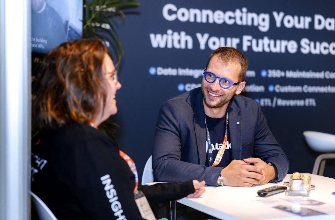 Two professionals engaged in conversation at the Data Expo conference booth, discussing data and AI solutions.