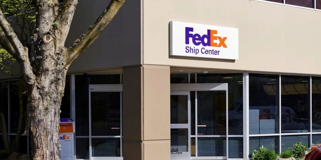 Exterior view of a FedEx Office storefront with a branded delivery van parked outside.